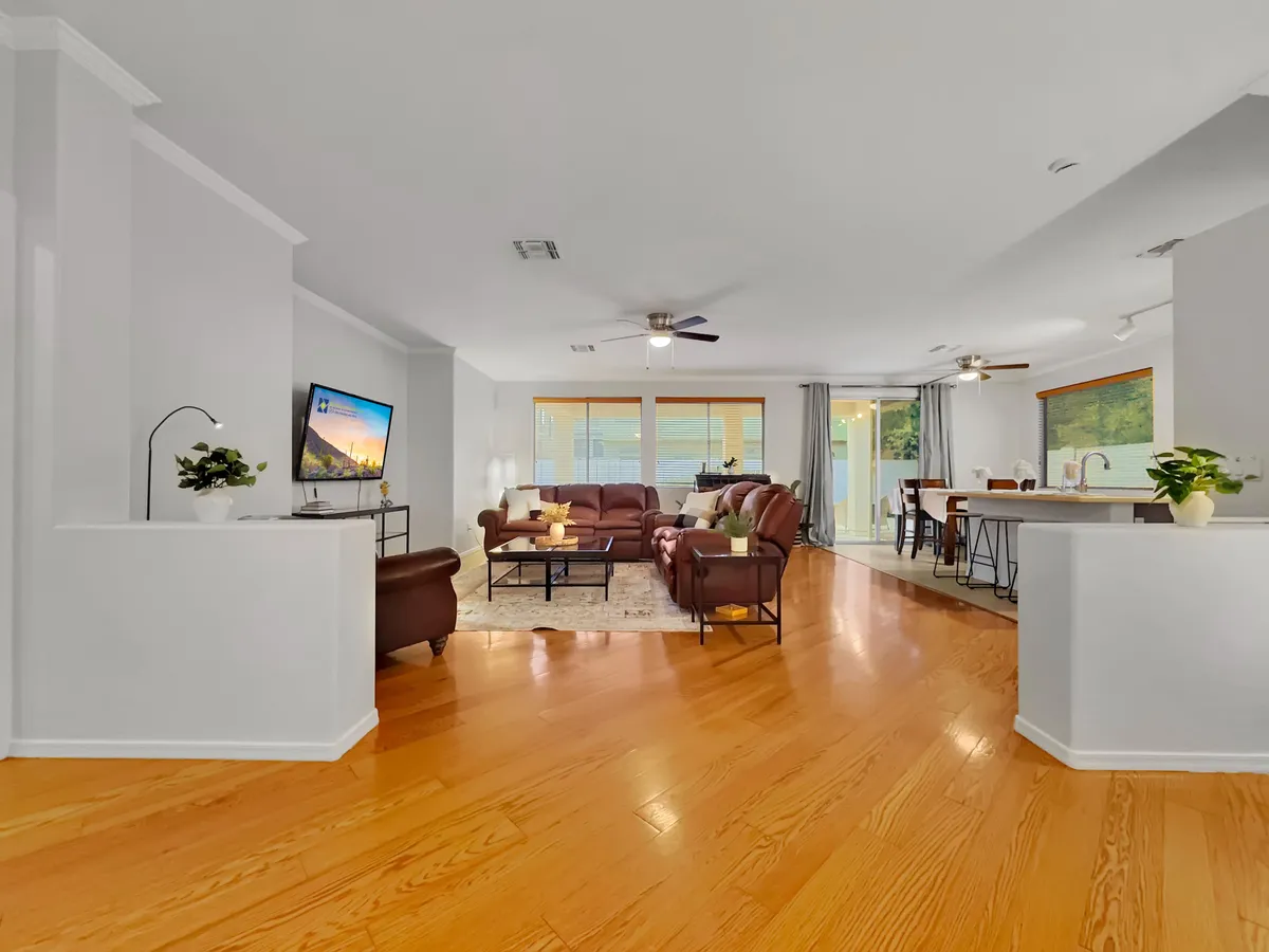 A spacious, open-concept interior with a large seating area, bright natural light streaming through big windows, and a kitchen bar visible in the background. The layout suggests ample room for group activities, casual dining, and entertaining friends.
