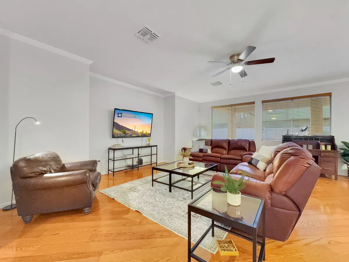 The scene centers on plush leather sofas arranged around a coffee table, with a TV and floor lamp enhancing the cozy atmosphere. A decorative plant adds a touch of greenery, and the space exudes warmth and relaxation, ideal for family movie nights or quiet moments after a day out.
