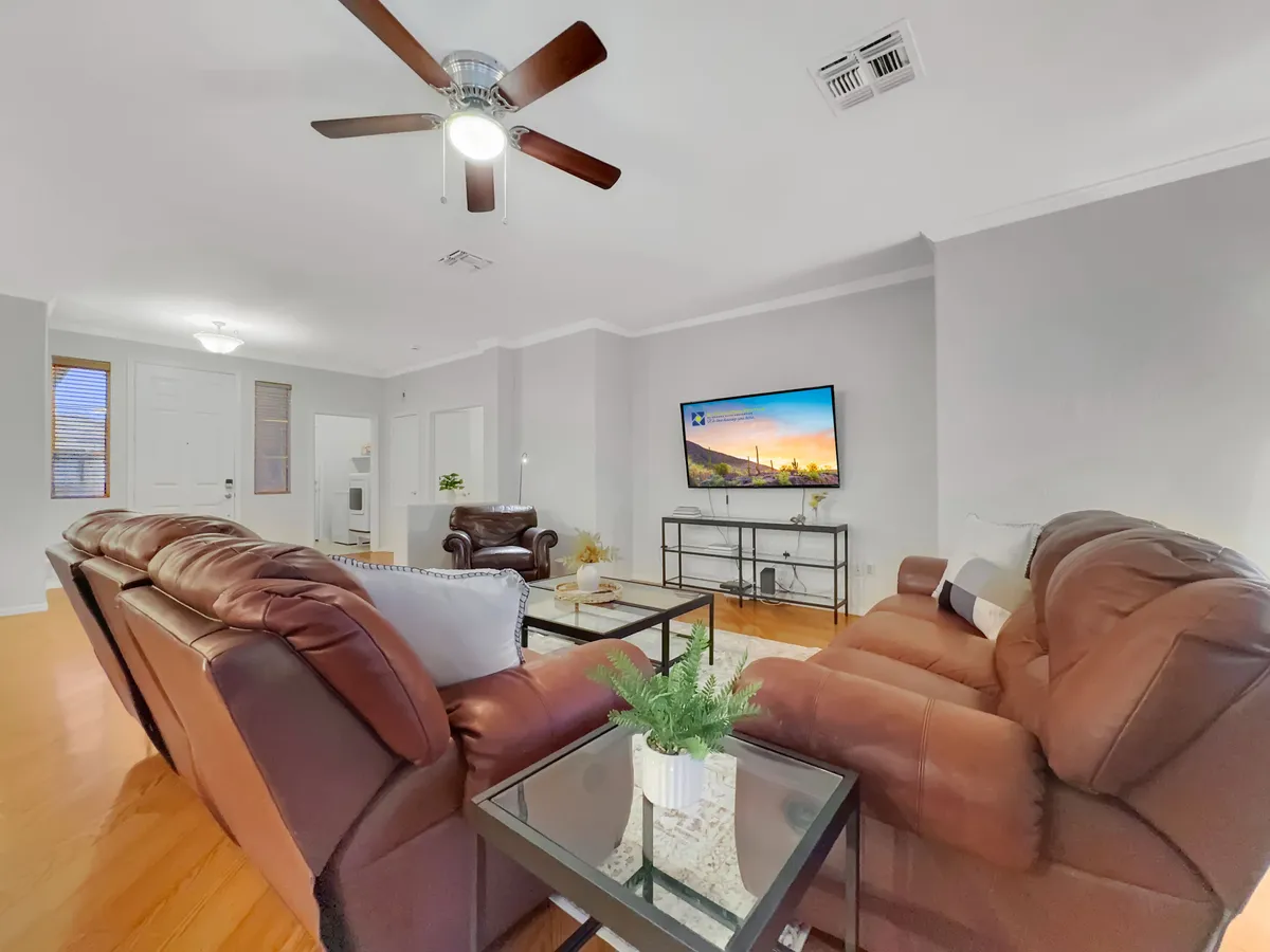 A cozy living room with leather sofas, coffee table, television, and a decorative plant, exuding a welcoming atmosphere ideal for movie nights or socializing.